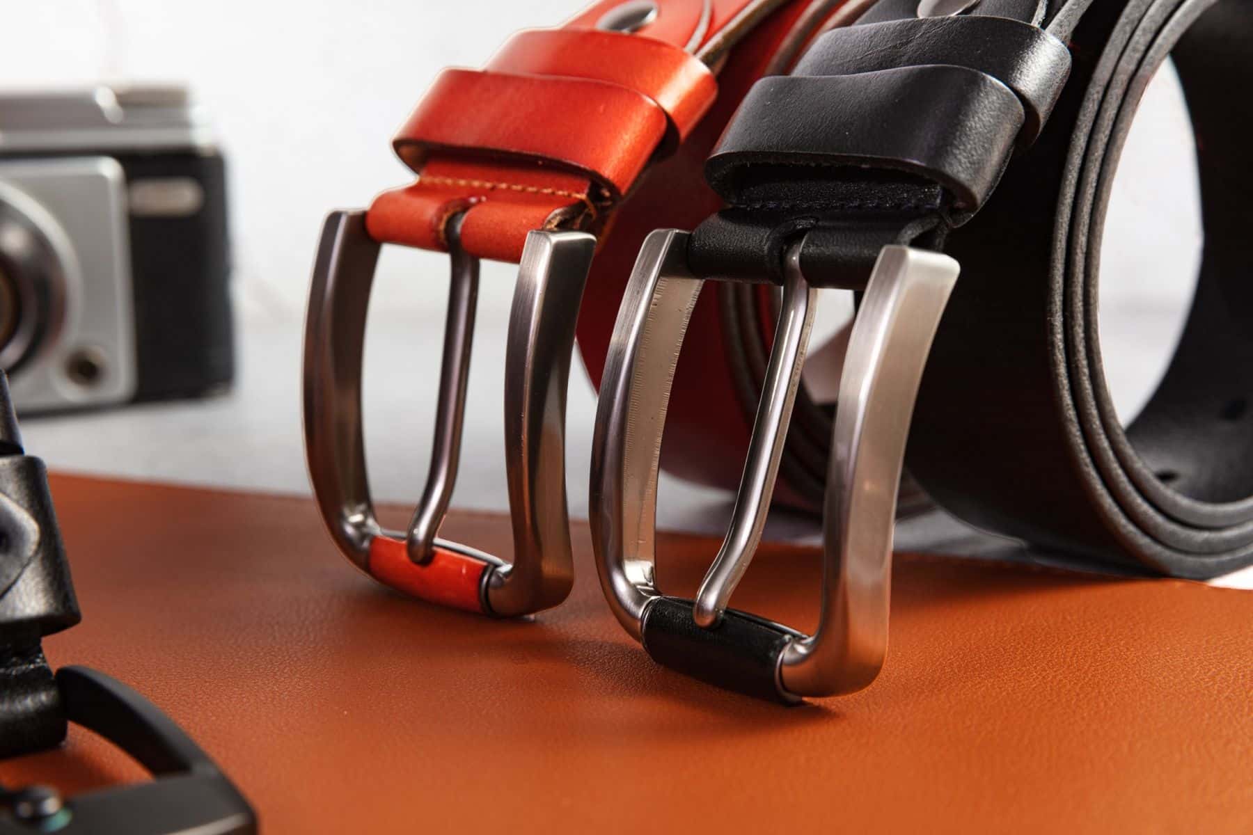 Two 40 mm leather jeans belts, orange-red and black, with brushed pin buckles