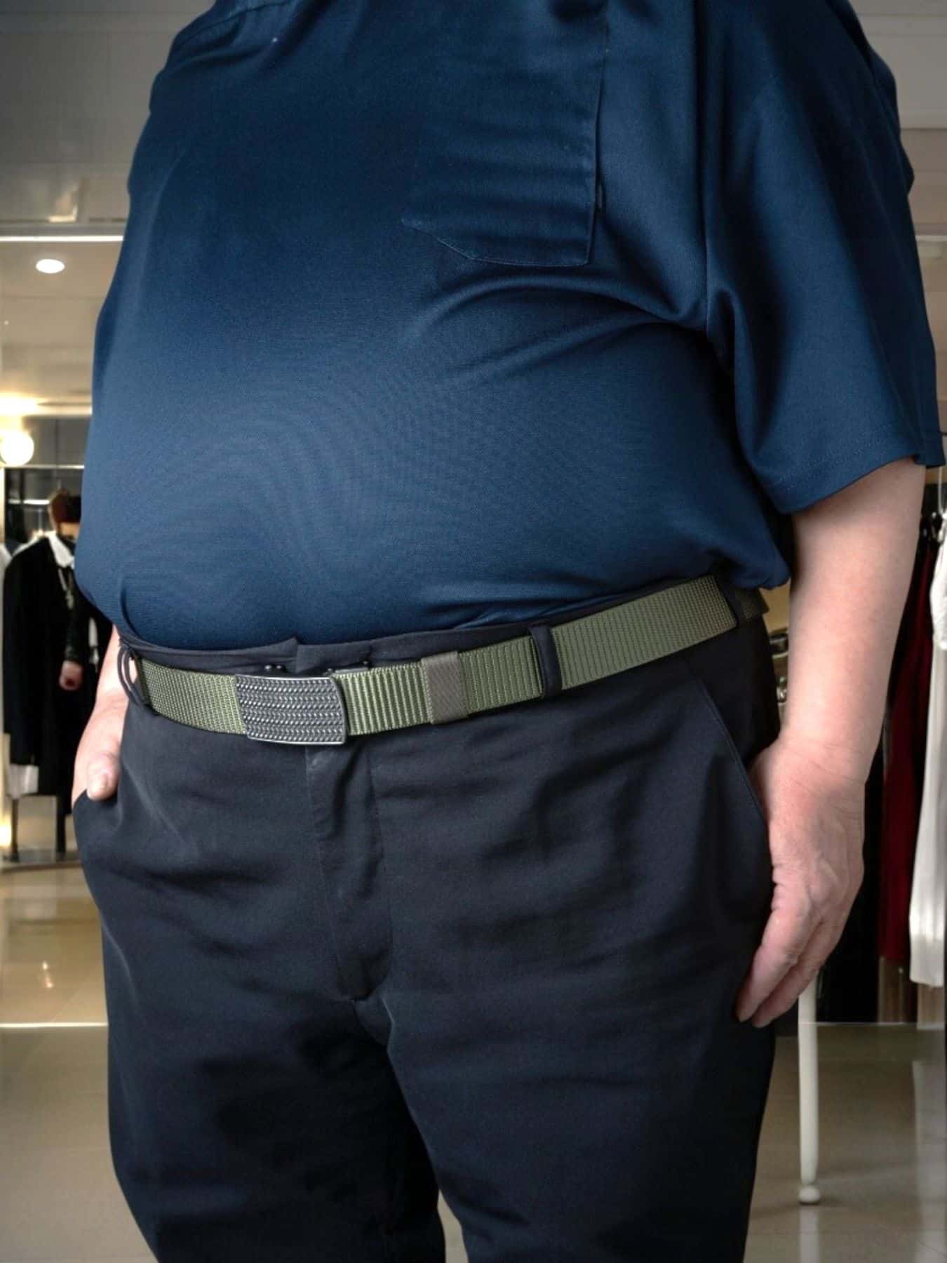 A big & tall man wearing an olive nylon webbing belt with a ratchet buckle